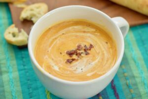 Roasted Butternut and Red Pepper soup in a bowl topped with crumbled bacon