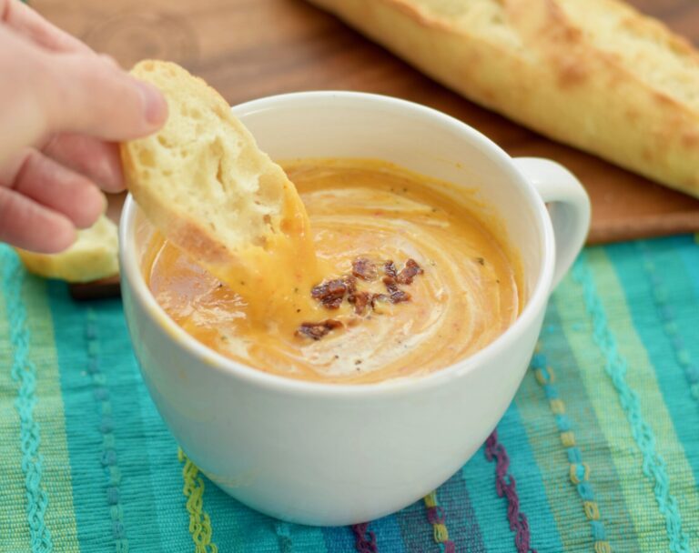Roasted Butternut and Red Pepper Soup in bowl with bread dipped in