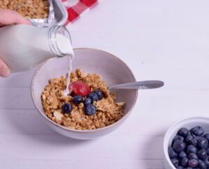 gluten free granola in bowl with milk being poured over it