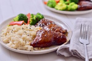low carb sesame ginger chicken on a plate with rice and vegetables