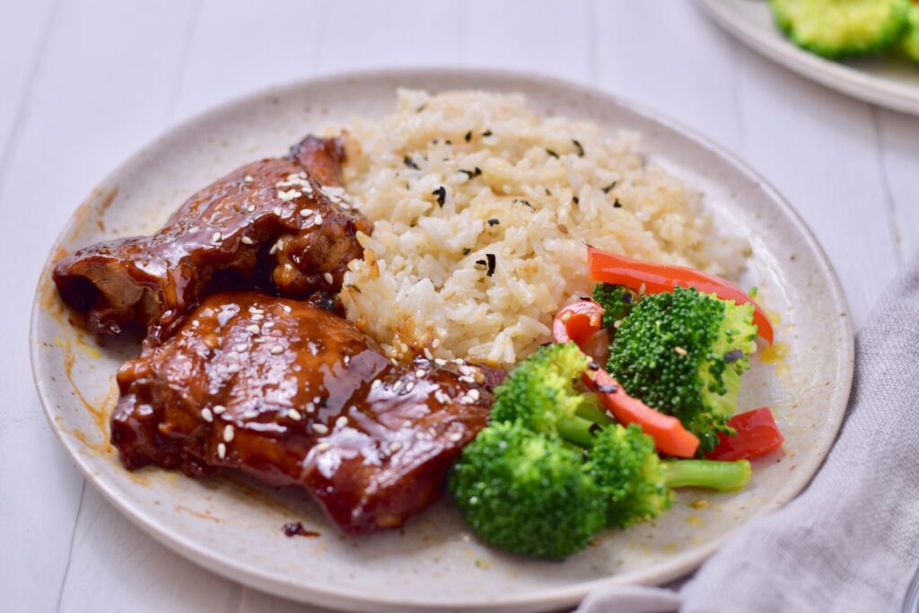  low carb sesame ginger chicken on a plate with rice and vegetables
