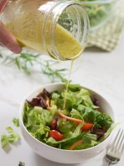 salad dressing pouring from jar onto salad