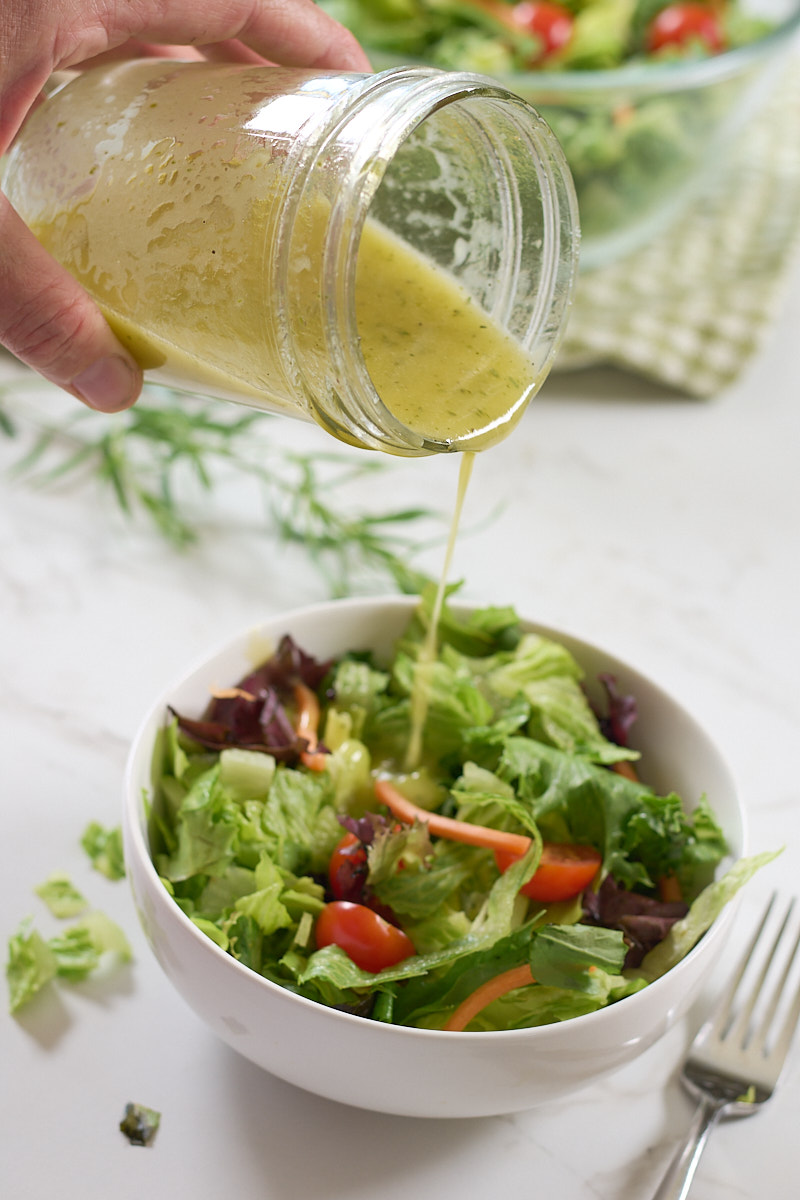 salad dressing pouring from jar onto salad